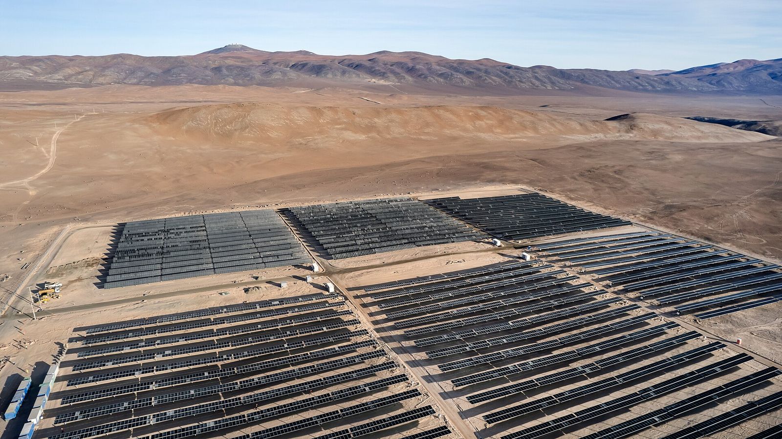 Vista aérea de la planta fotovoltaica Paranal-Armazones, con filas de seguidores solares en el desierto de Atacama y cerros al fondo